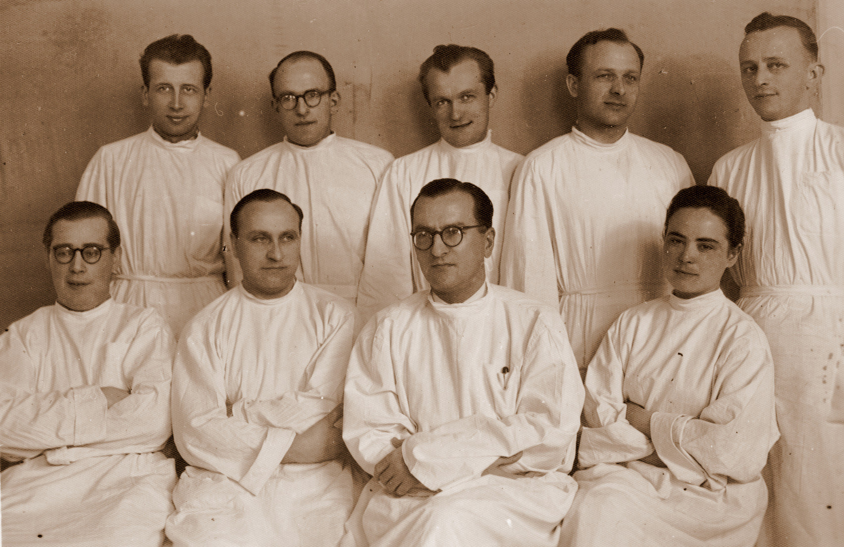 Dziewięciu mężczyzn, jedna kobieta. Wszyscy w białych lekarskich kitlach. Zdjęcie archiwalne